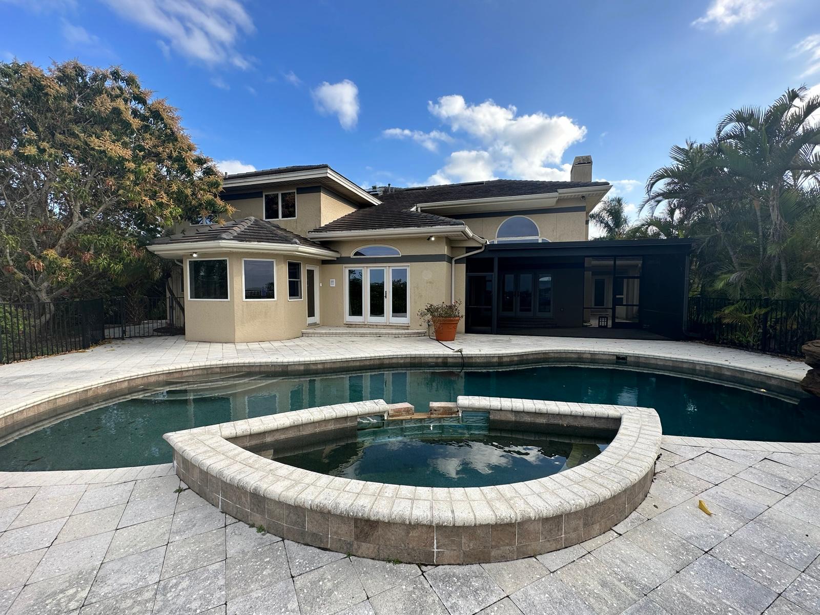 Wide view of pool, spa and paver patio with screened lanai