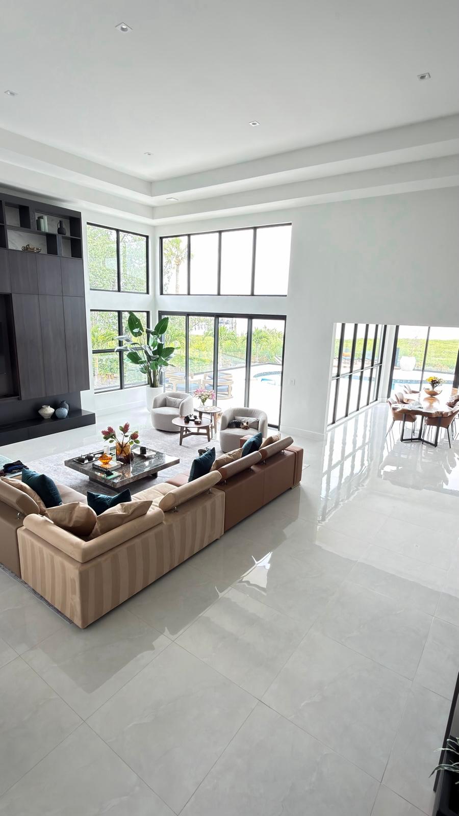 Bright double-height living room with dark built-in media wall and porcelain floors