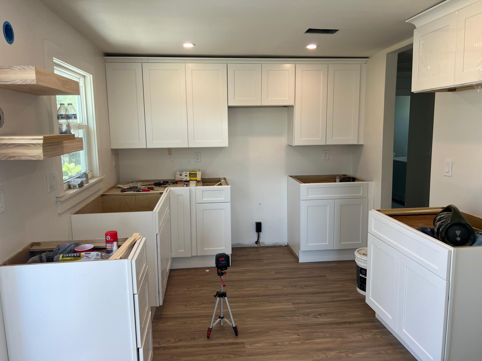 White shaker kitchen cabinets and vinyl plank flooring, install in progress