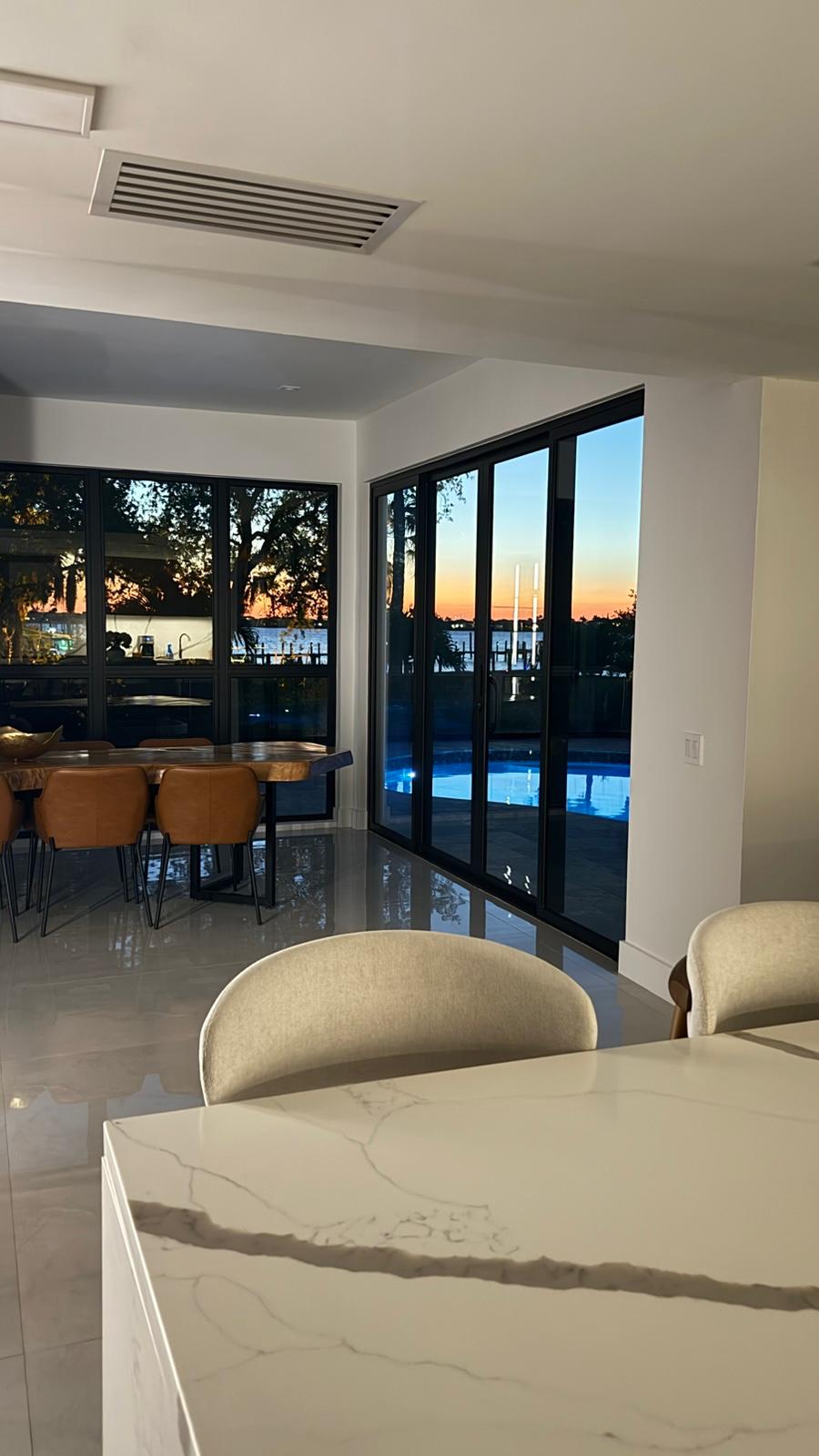 Kitchen island in marble-look quartz with sunset waterfront view through black-framed glass
