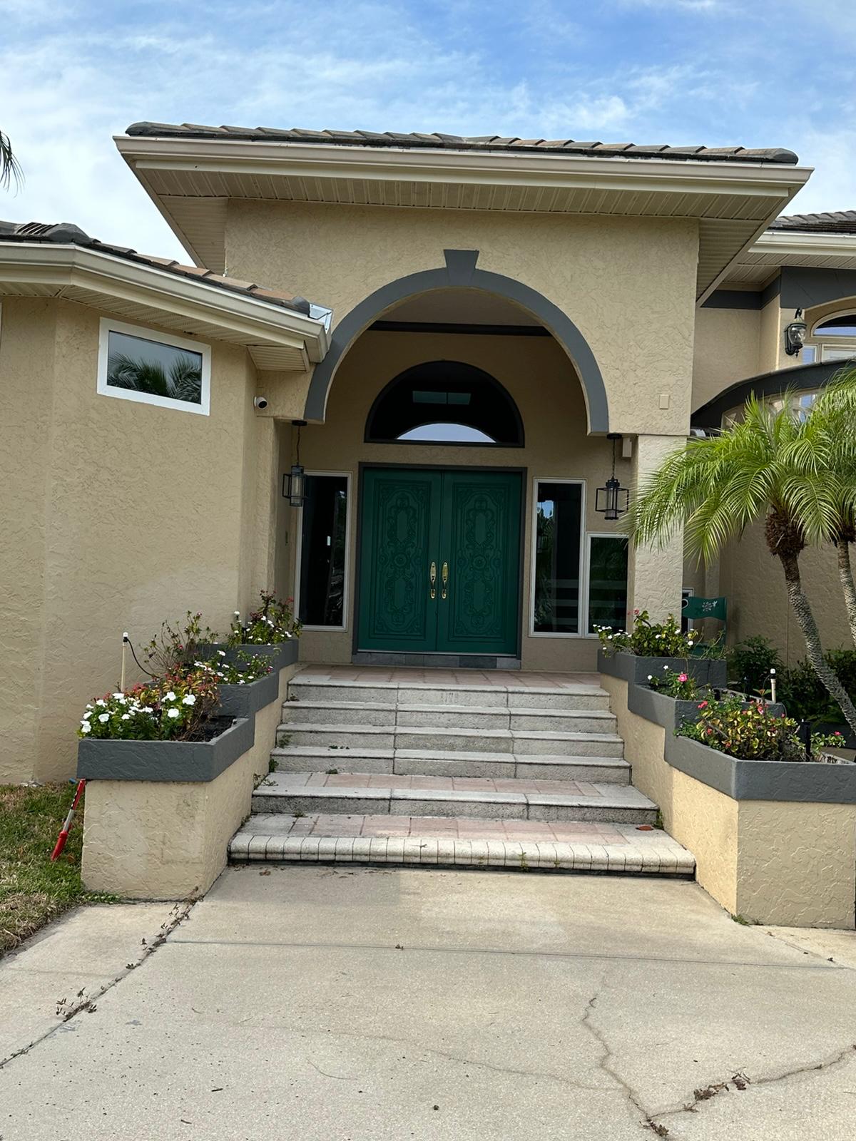 Arched entry with green double doors and dated steps before remodel