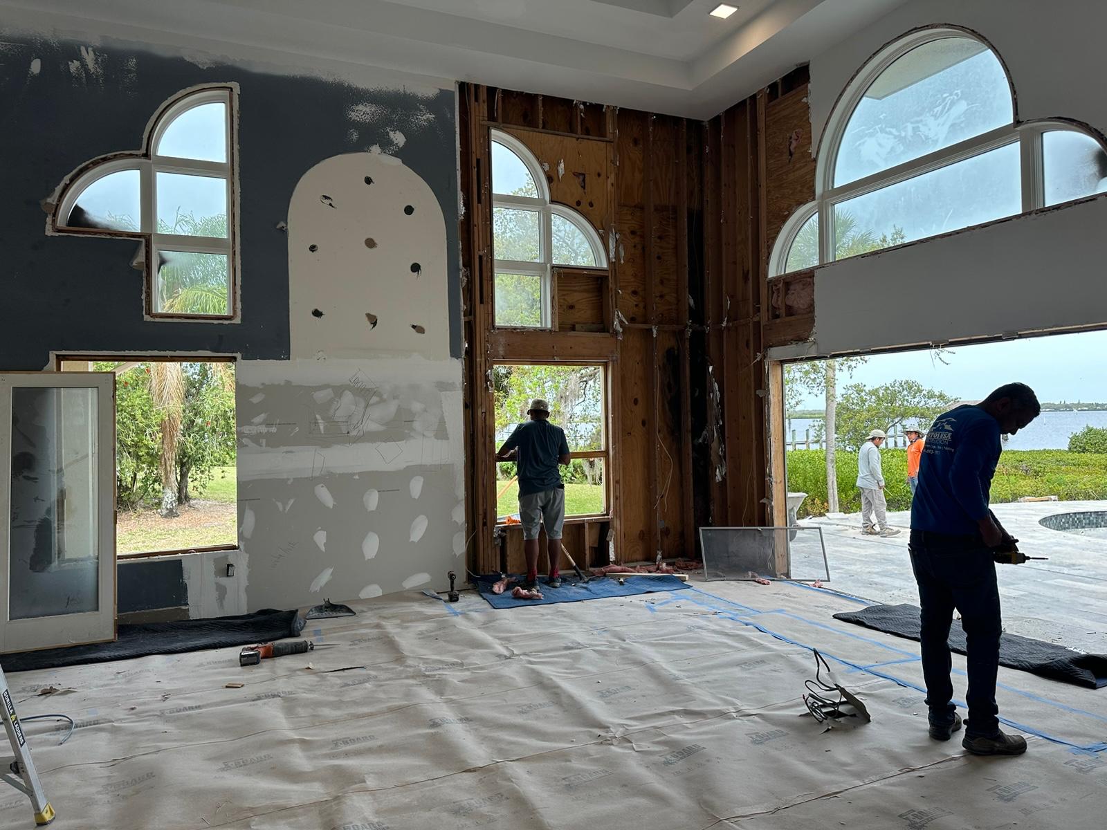 Crew removing arched windows and framing during a full interior renovation