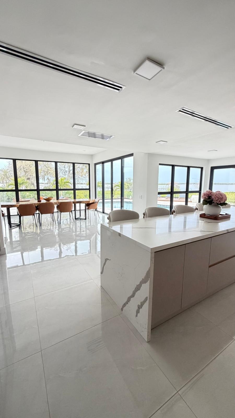 Kitchen island in white quartz opening to dining area with bay views