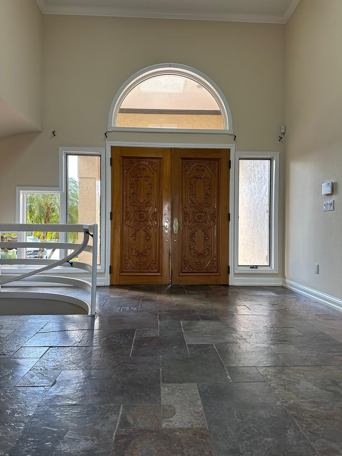 Two-story entry with slate stone tile floor and carved wood double doors