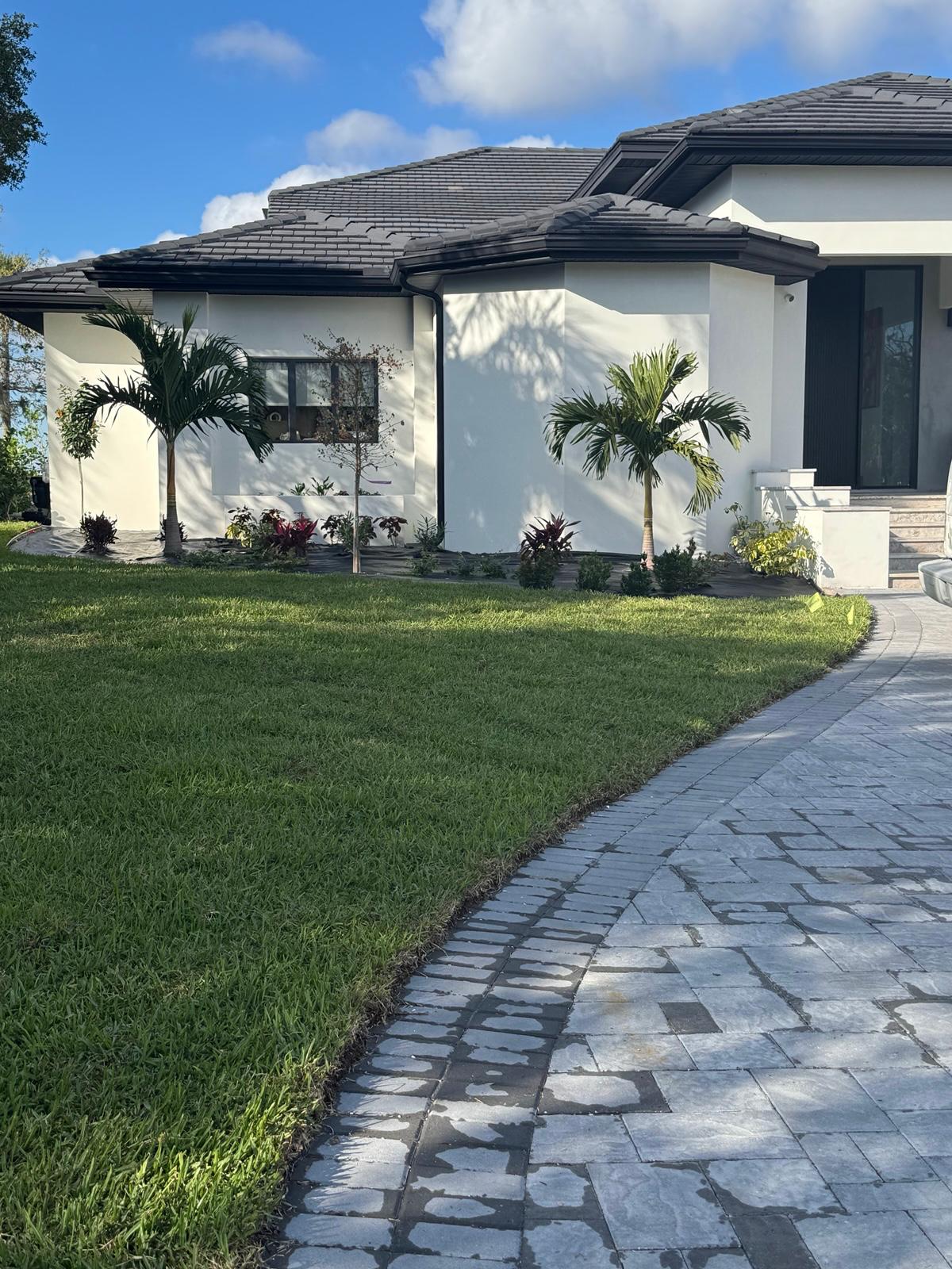 Finished white stucco home with new sod lawn and stamped paver walkway