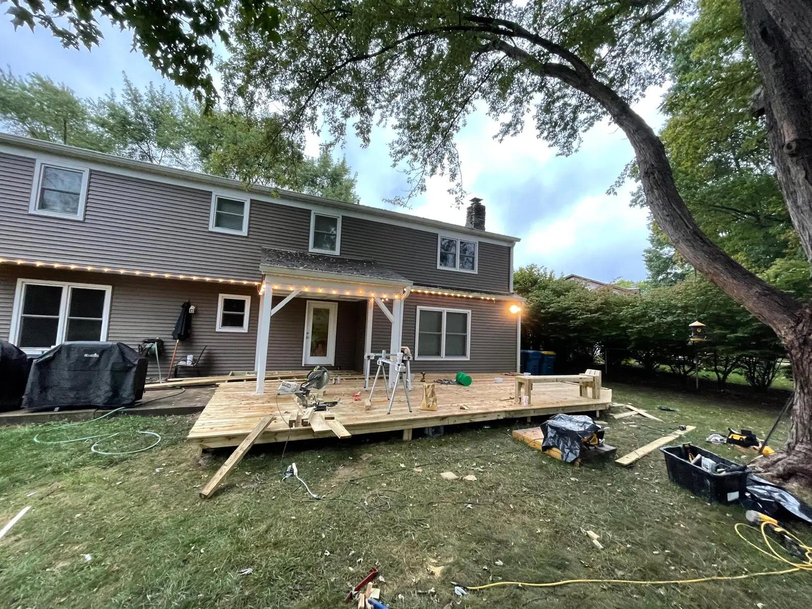 New pressure-treated wood deck built off the back of a two-story home at dusk