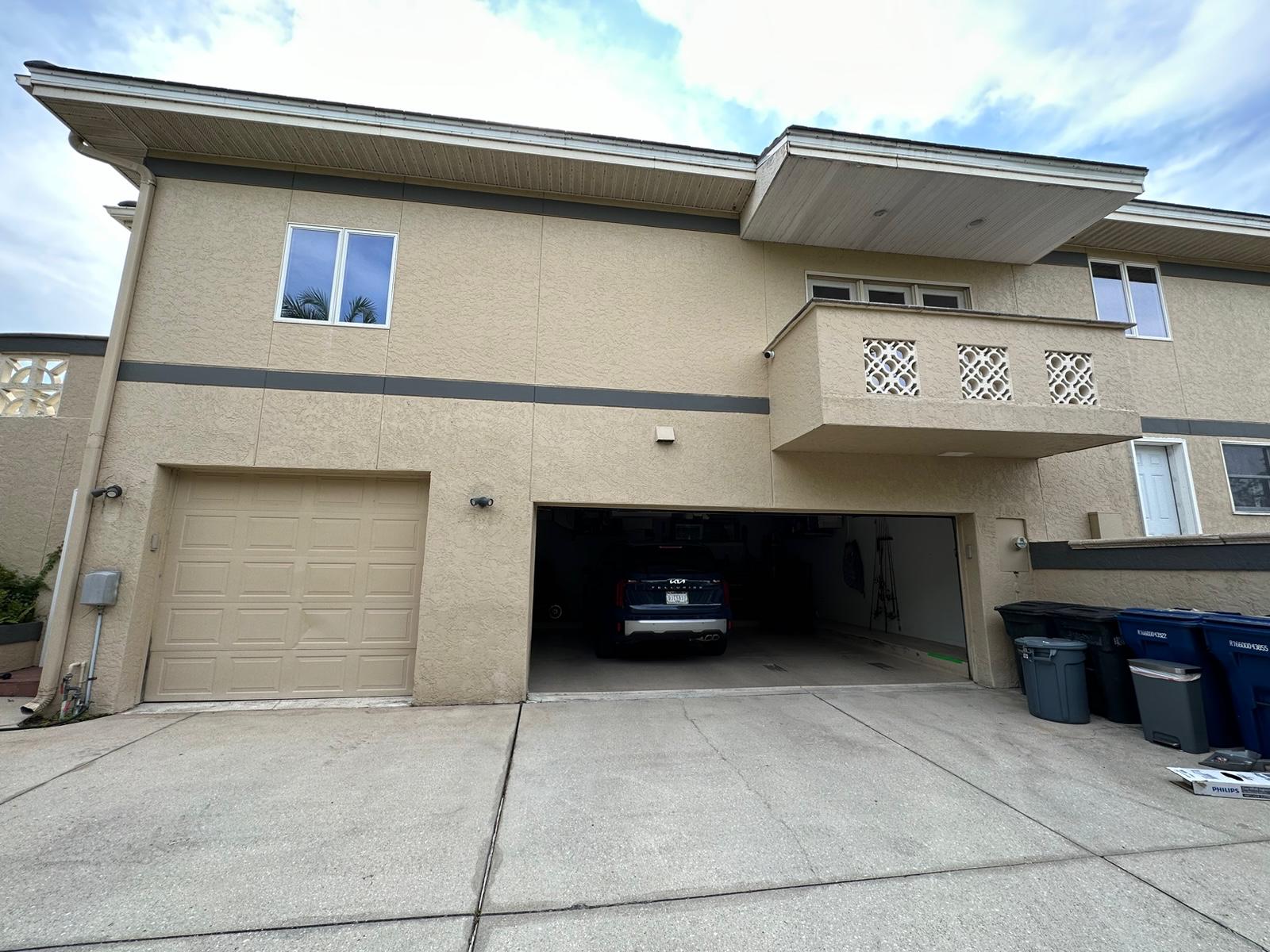 Garage bays and balcony on tan stucco elevation before repaint