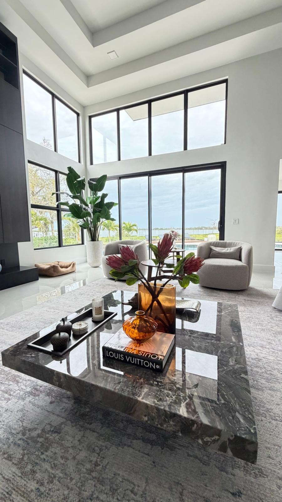 Double-height living room with black window walls and marble coffee table