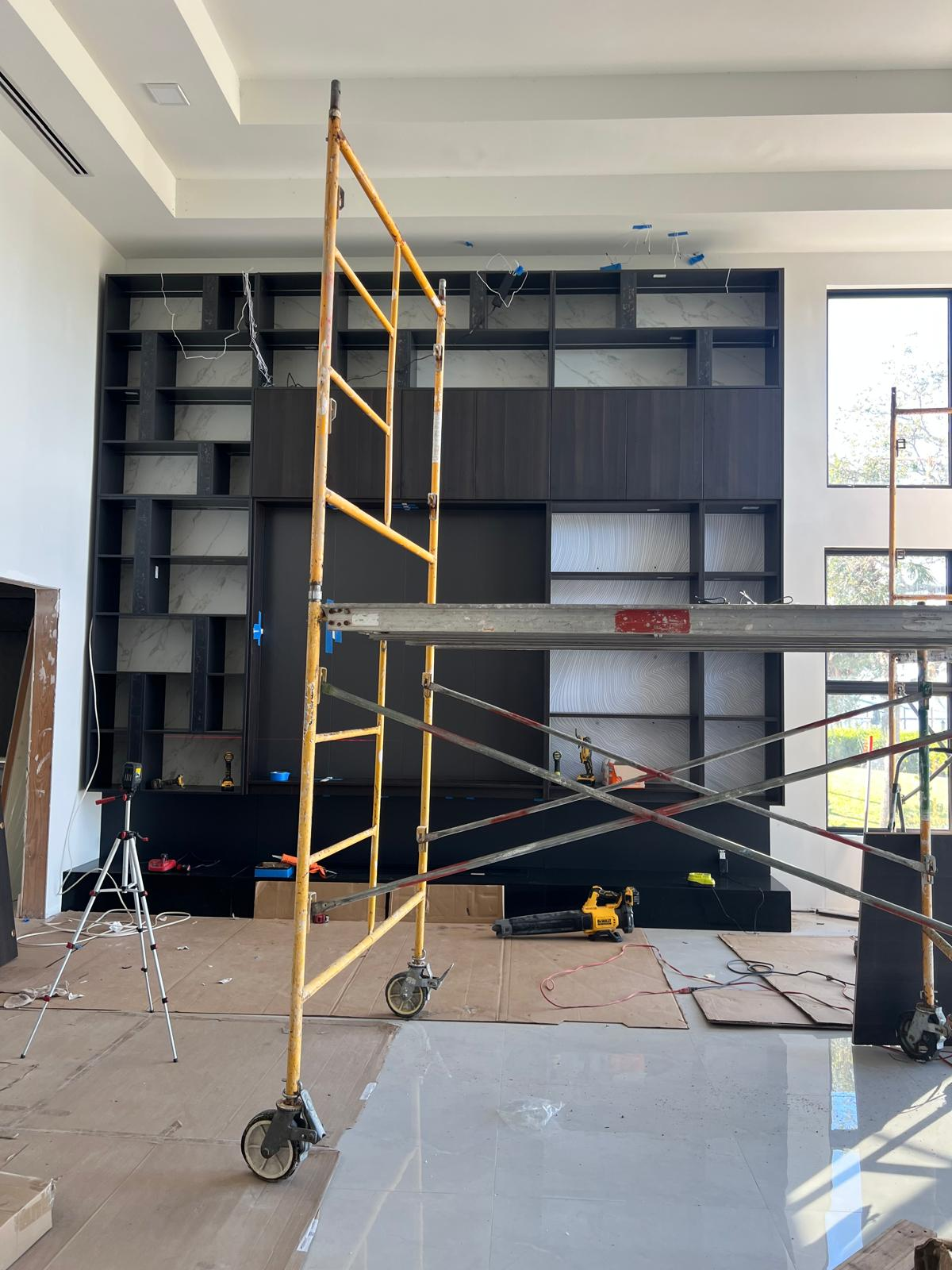 Wide view of custom black built-in wall with marble panels and integrated cabinetry