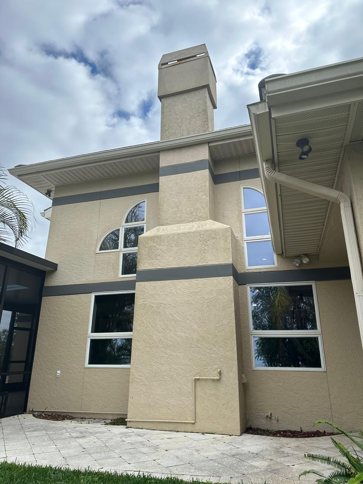 Two-story stucco exterior with fresh paint, dark banding and new gutters