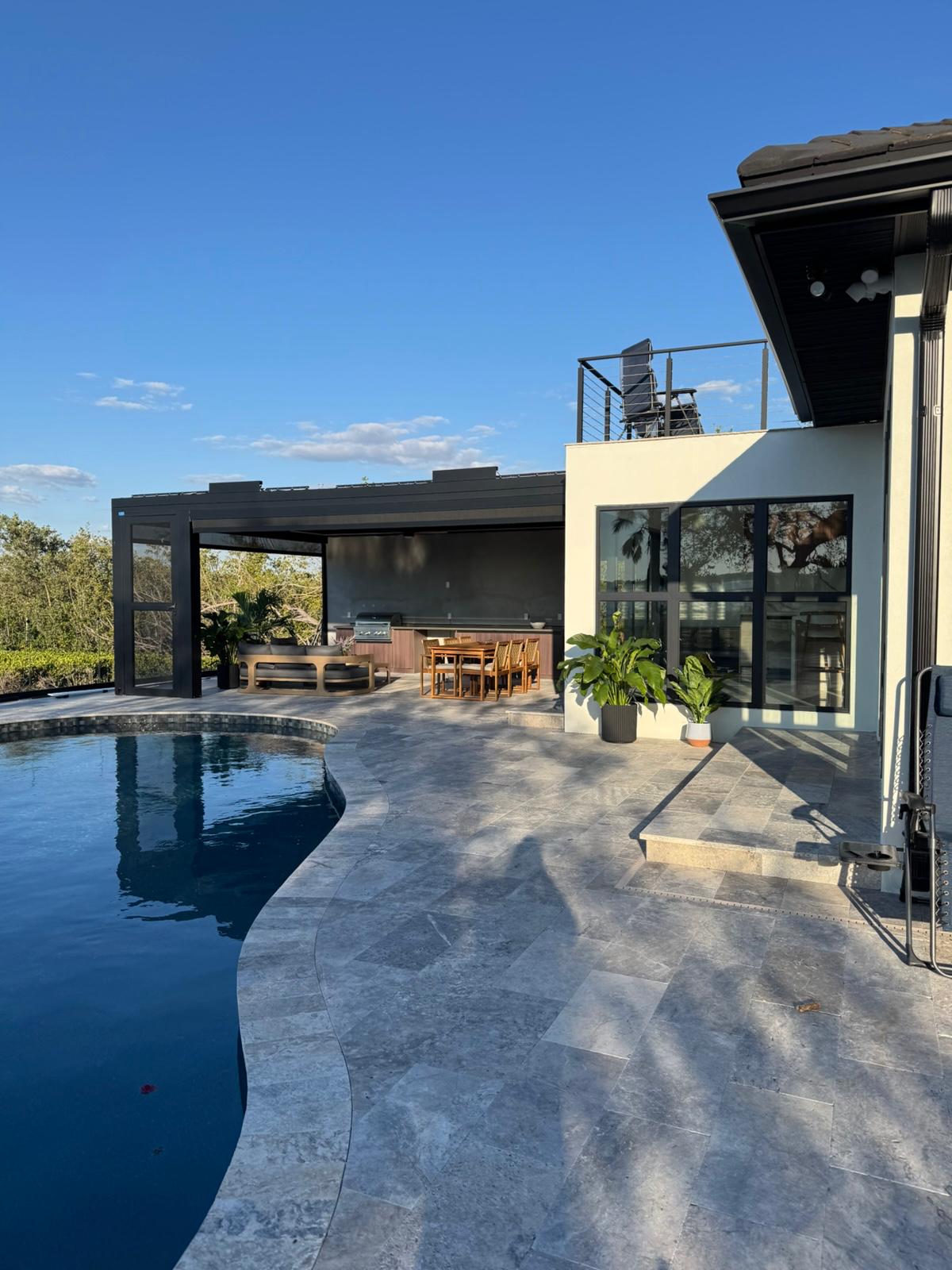Pool deck with louvered pergola, grill station and travertine paving