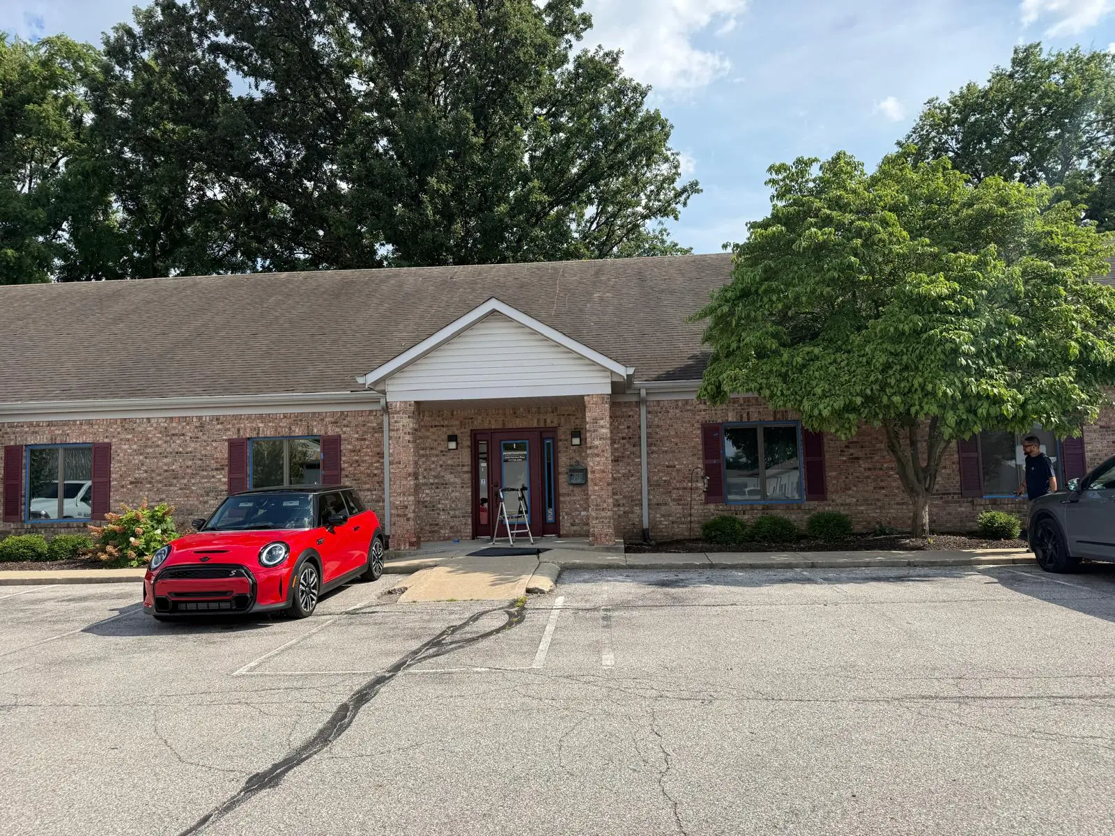 Brick office exterior before repaint with tan roofline, red shutters and original facade colors