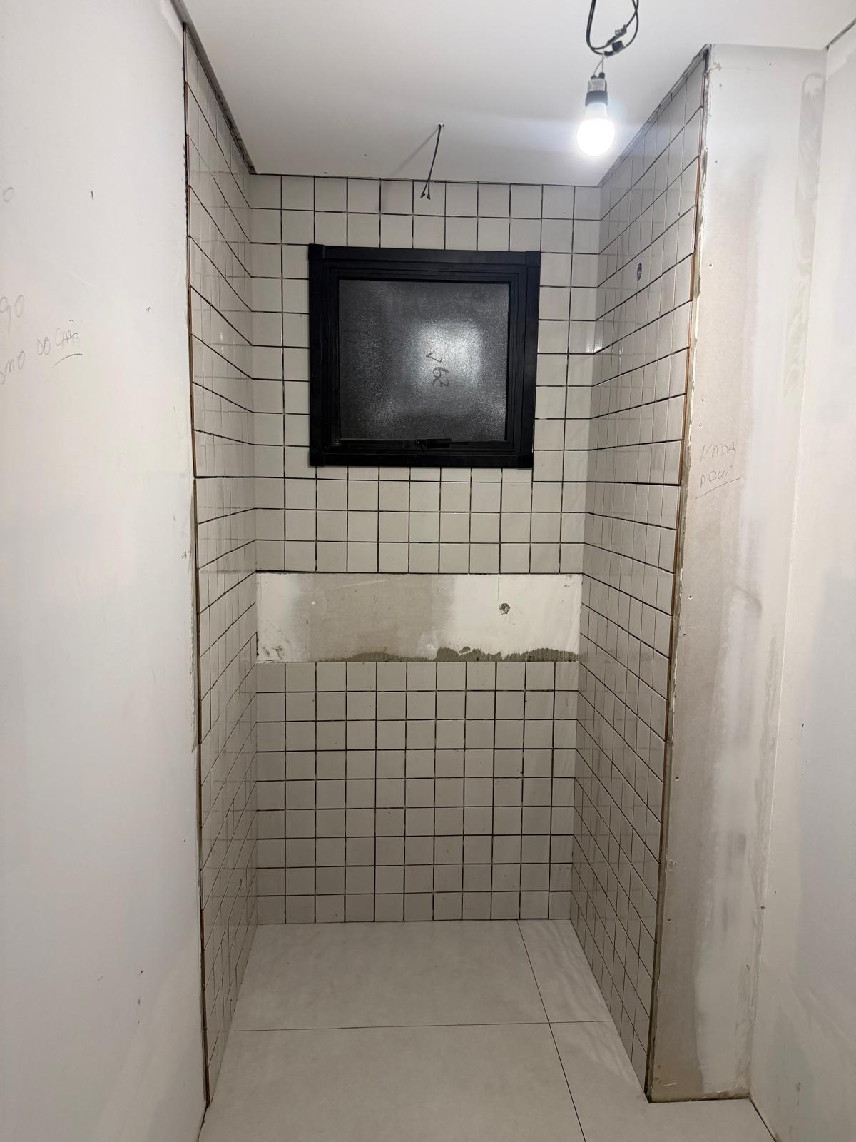 White subway tile bathroom with dark grout, mid-install