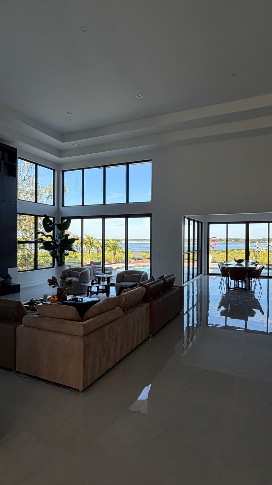 Double-height living room with black window walls facing the water