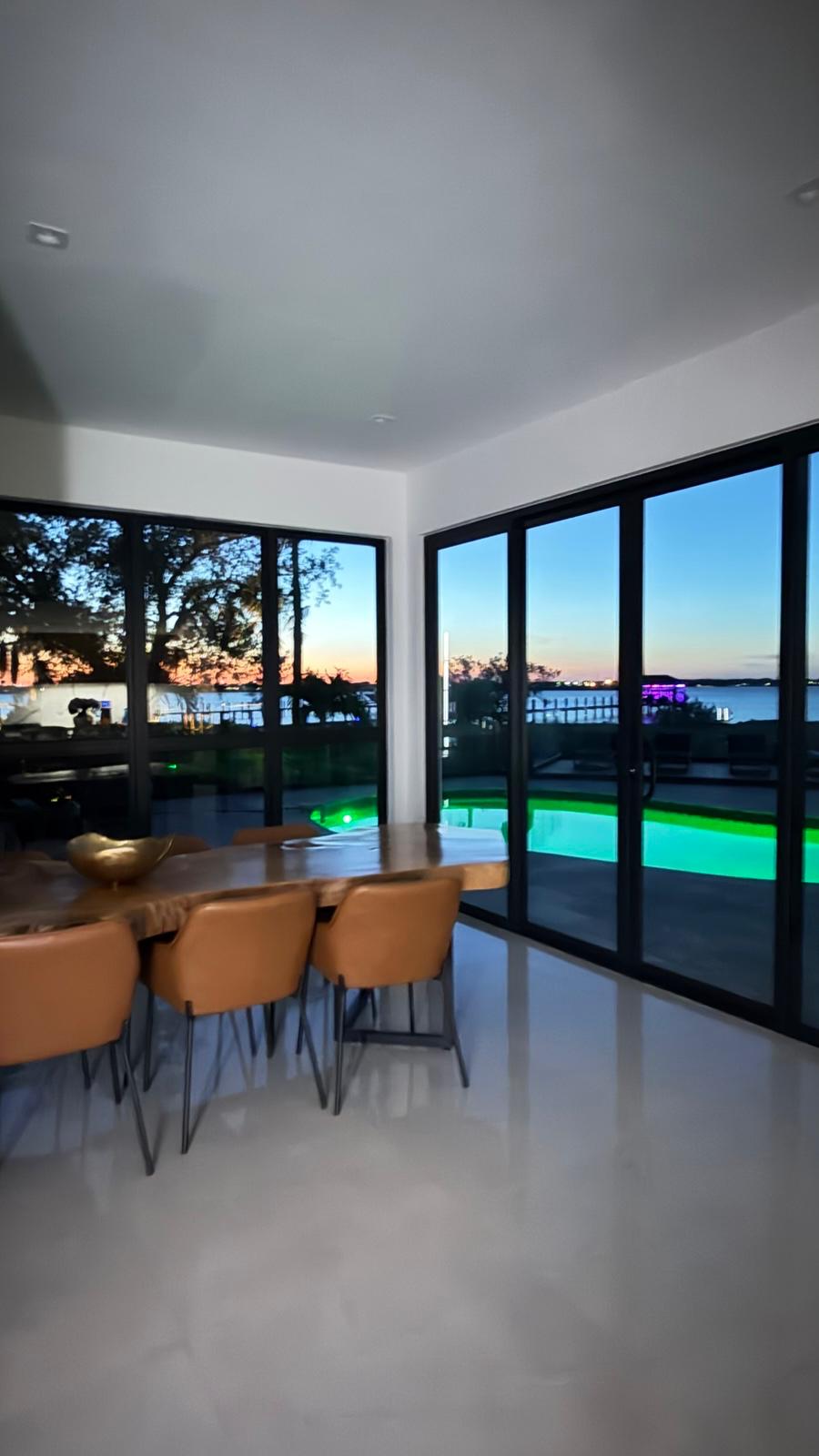 Dining area at dusk with live-edge table and lit pool beyond sliding glass doors