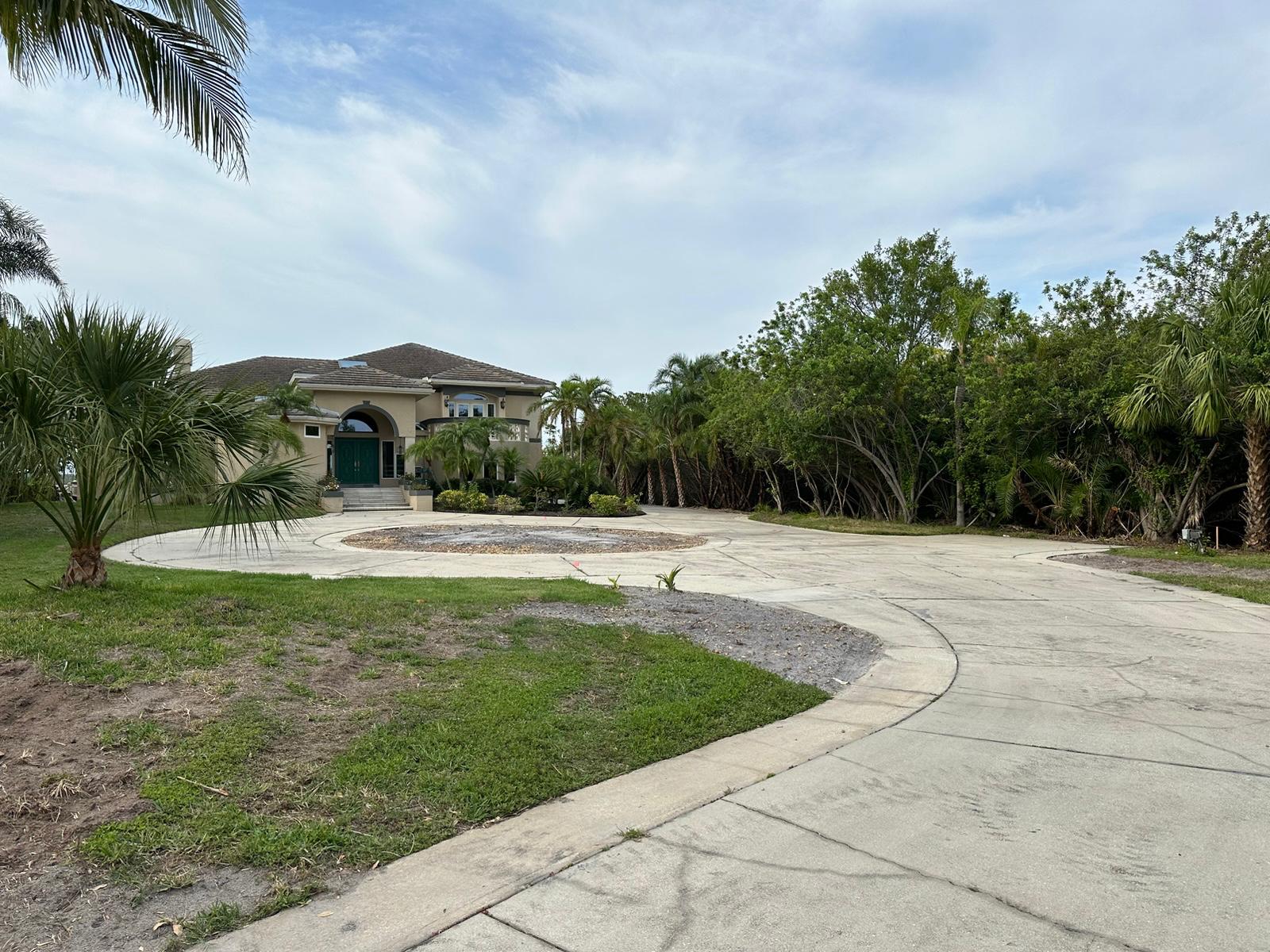 Approach to tan stucco home showing driveway before resurfacing