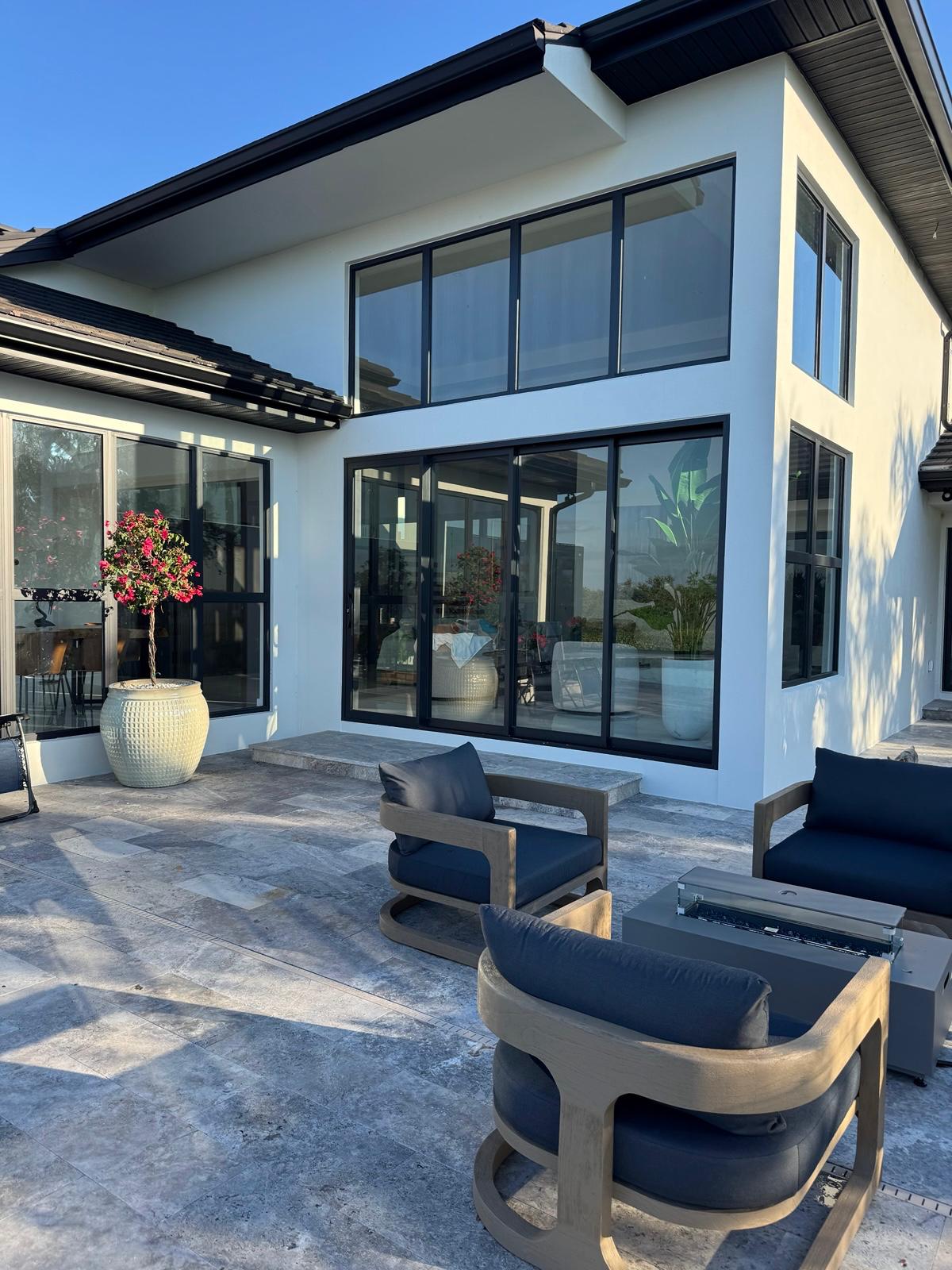 Outdoor lounge with fire pit table on travertine patio beside white stucco walls