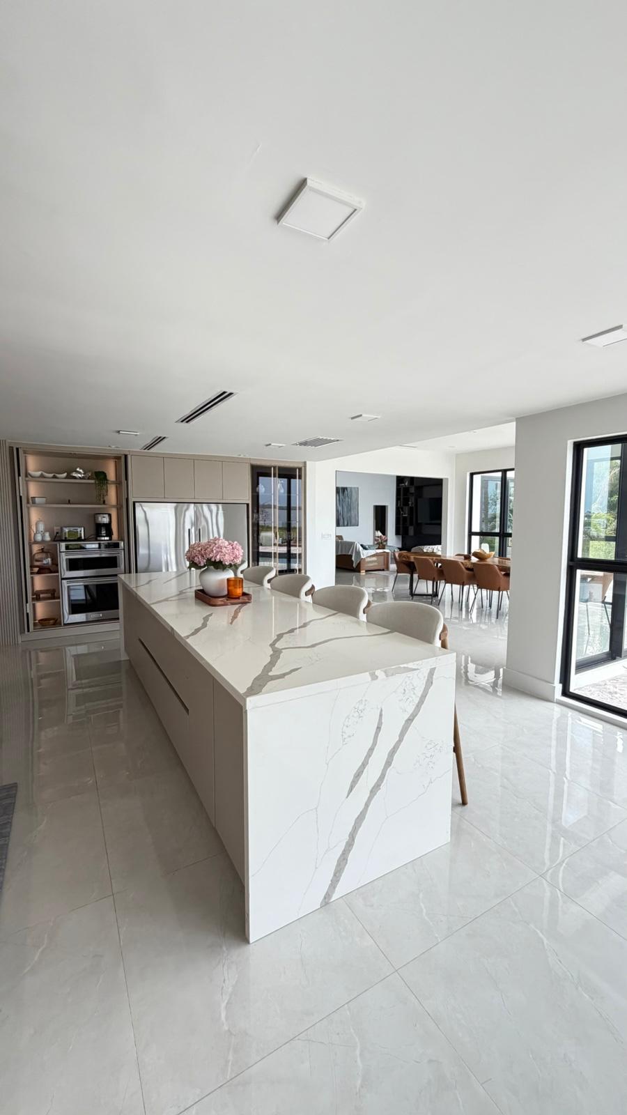 Handleless kitchen with calacatta quartz waterfall island and integrated pantry wall