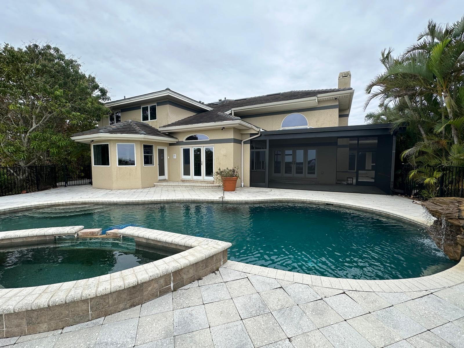 Backyard pool with rock waterfall feature and finished paver deck