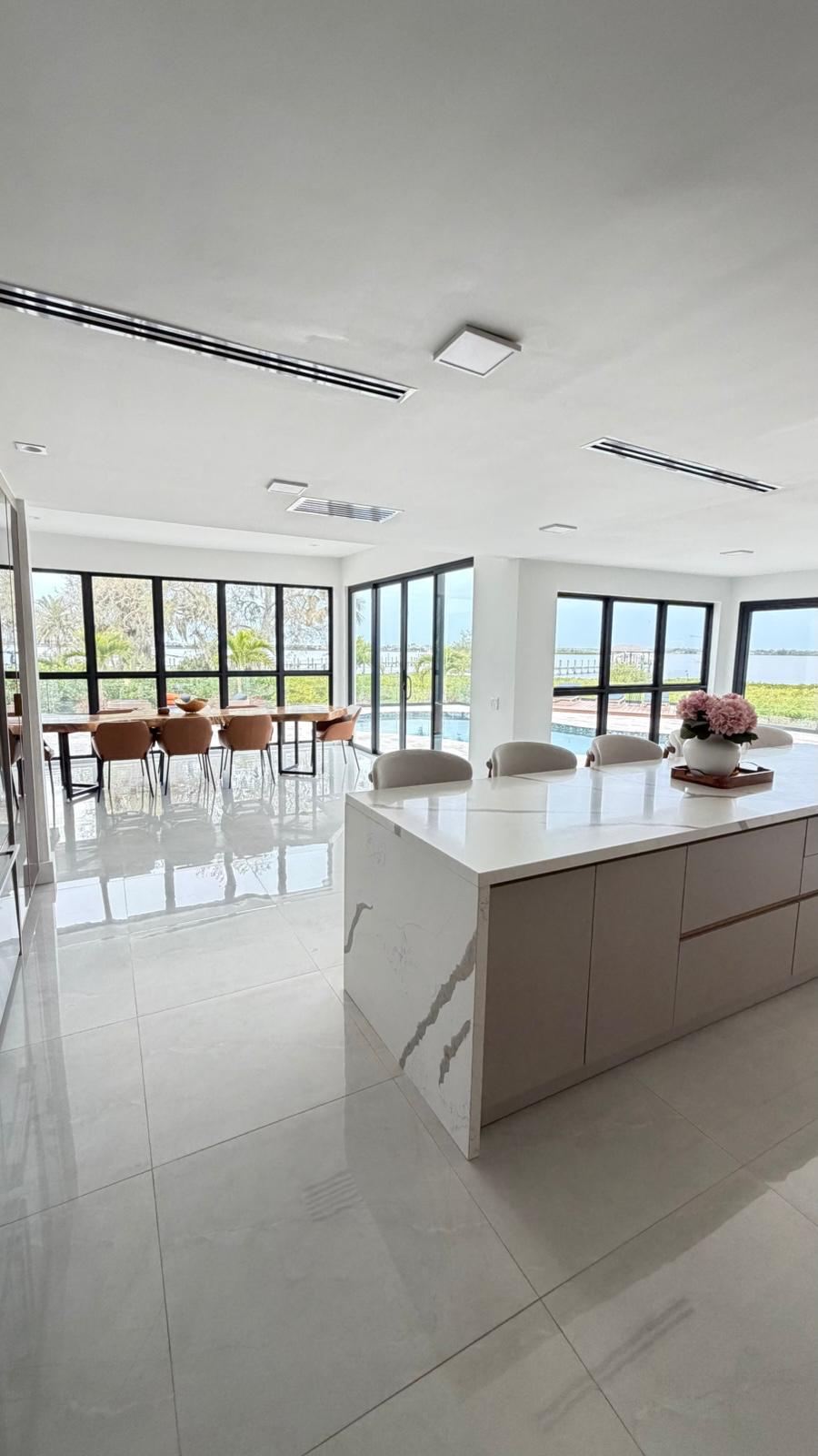 Wide view of quartz island kitchen with polished porcelain floor and water view