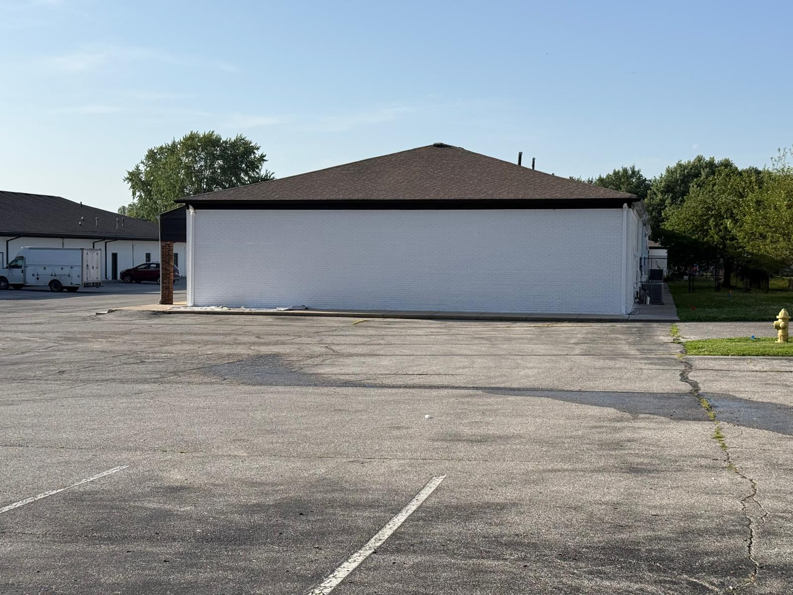 Side elevation of freshly painted white brick commercial building with dark fascia