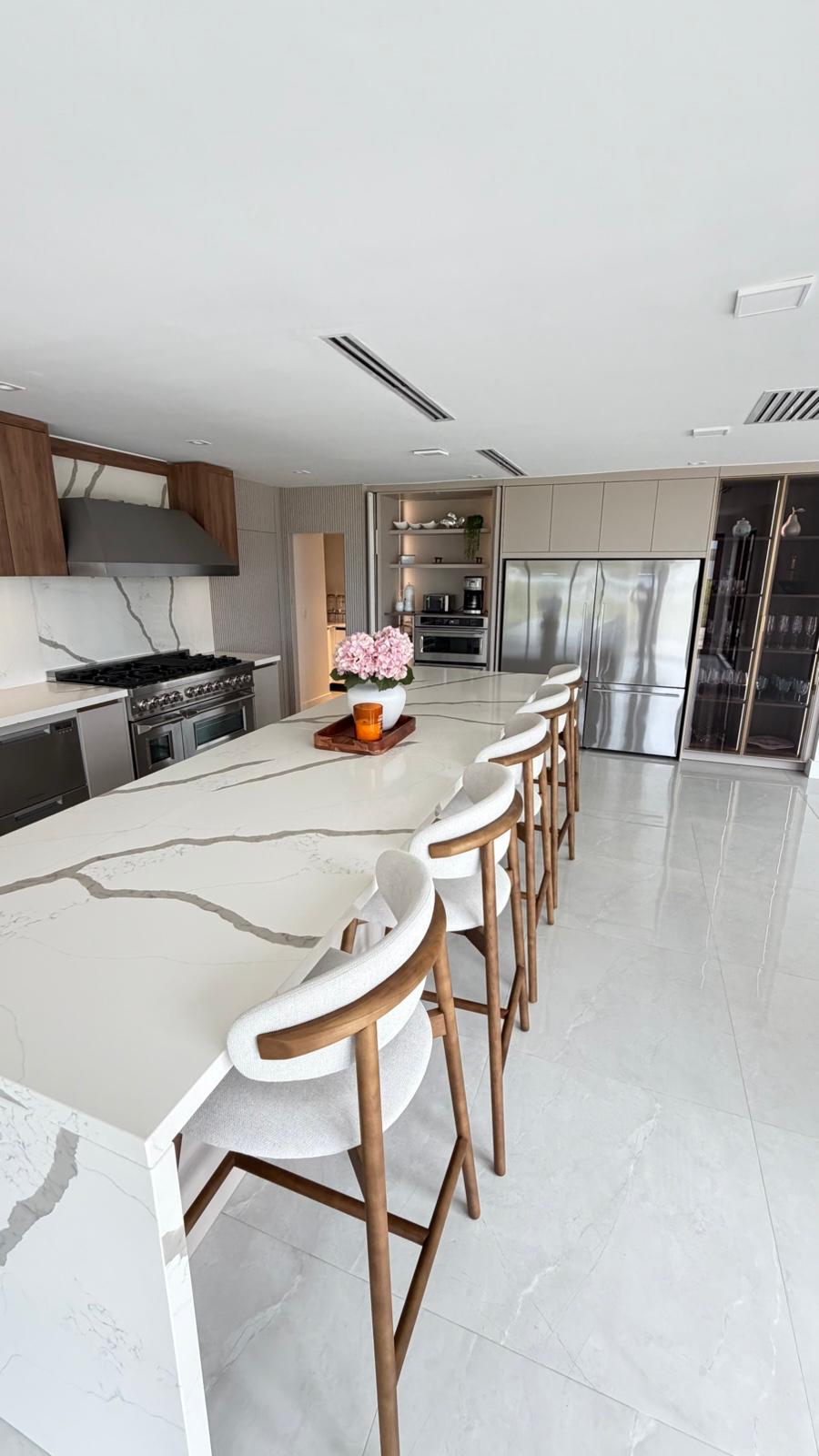 Modern kitchen with long quartz waterfall island, walnut cabinetry and pro range