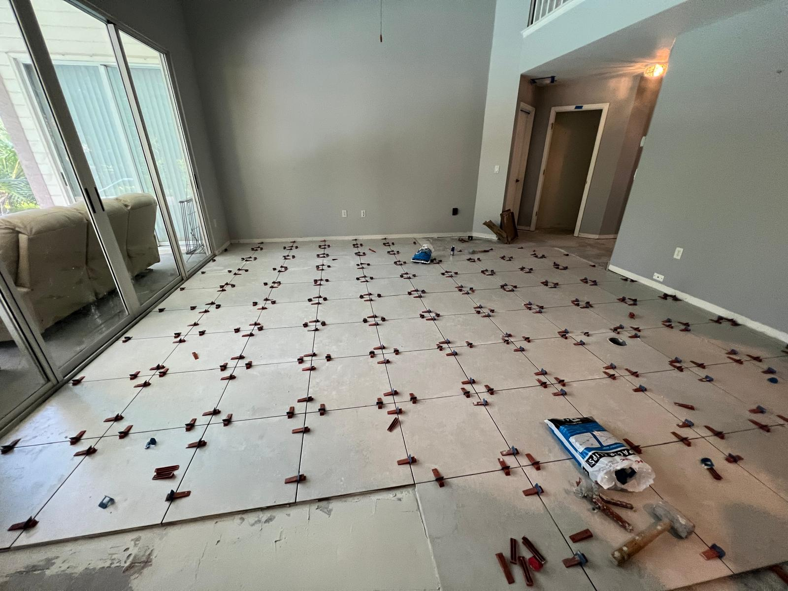 Large-format tile floor being installed with leveling clips in a great room