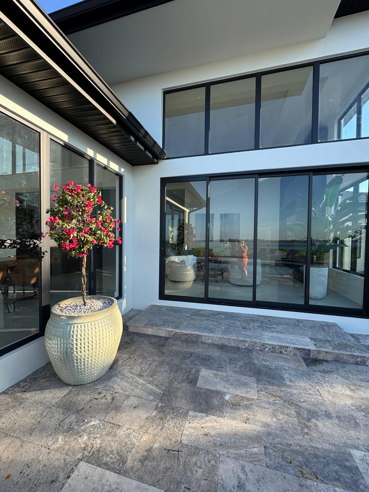 Travertine patio corner with black-framed glass and potted bougainvillea