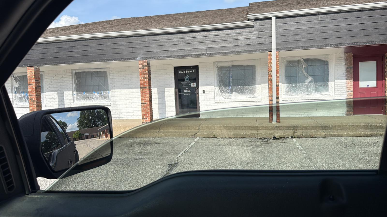 Storefront exterior with freshly painted dark charcoal siding over brick