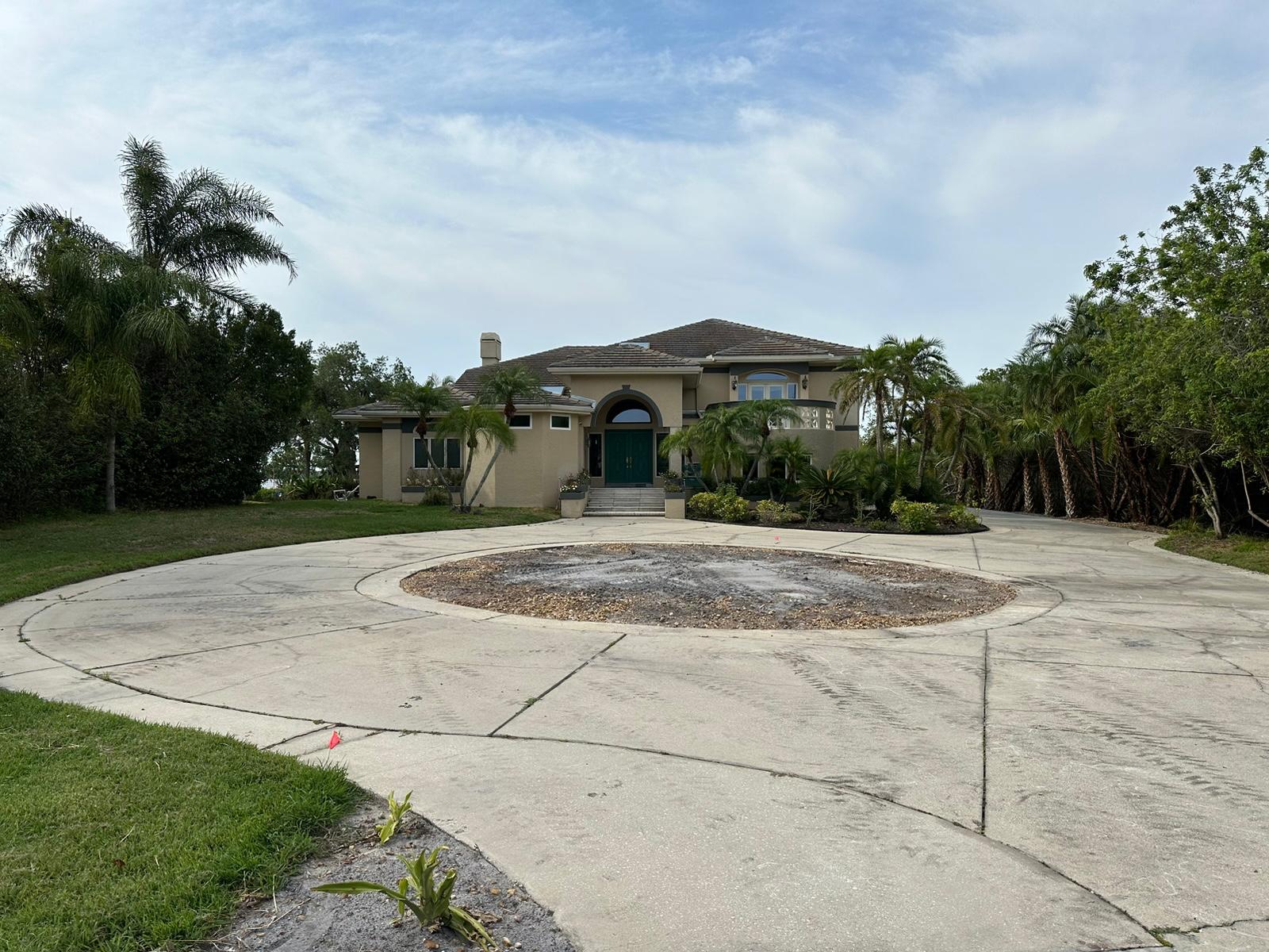 Wide driveway view of tan stucco home before landscaping work